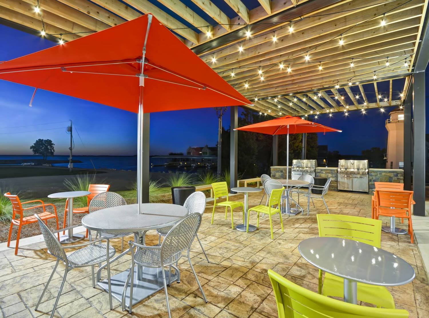 Outdoor Patio Grilling Station with Chairs, Umbrella Tables and Grills at Night